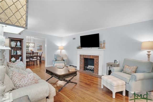 living room with crown molding, a fireplace, and light hardwood / wood-style flooring