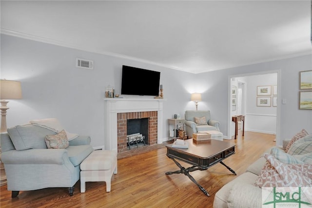 living room with ornamental molding, a brick fireplace, and light hardwood / wood-style floors