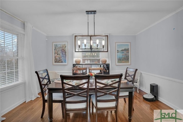 dining area featuring hardwood / wood-style flooring, crown molding, and a chandelier