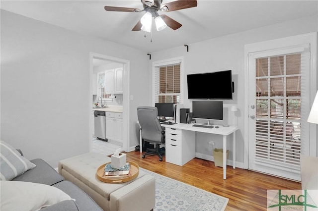 office space with ceiling fan, sink, and light wood-type flooring