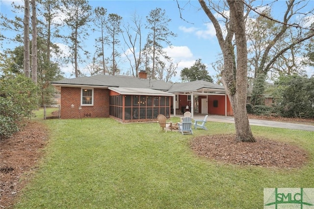 back of house featuring a yard, a fire pit, and a sunroom