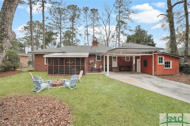 back of house with an outdoor fire pit, a sunroom, and a lawn