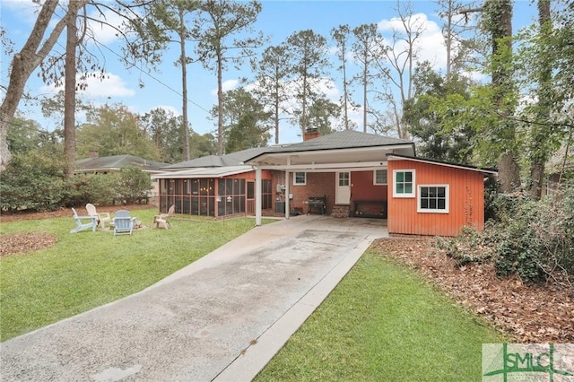 back of property with a carport, a sunroom, and a yard