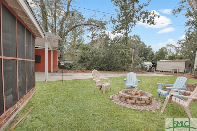 view of yard featuring a sunroom, a patio area, and a fire pit