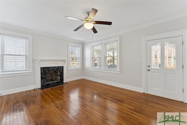 unfurnished living room with crown molding, wood-type flooring, a premium fireplace, and ceiling fan