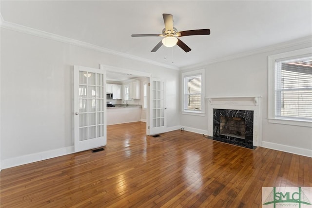 unfurnished living room featuring crown molding, ceiling fan, a high end fireplace, and hardwood / wood-style floors