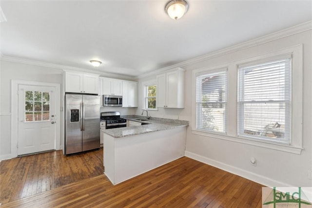 kitchen with dark hardwood / wood-style flooring, stainless steel appliances, kitchen peninsula, and white cabinets