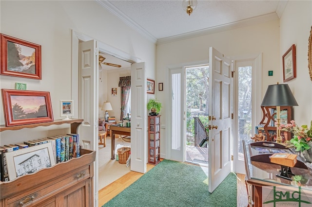 foyer entrance featuring crown molding, a textured ceiling, and light hardwood / wood-style floors