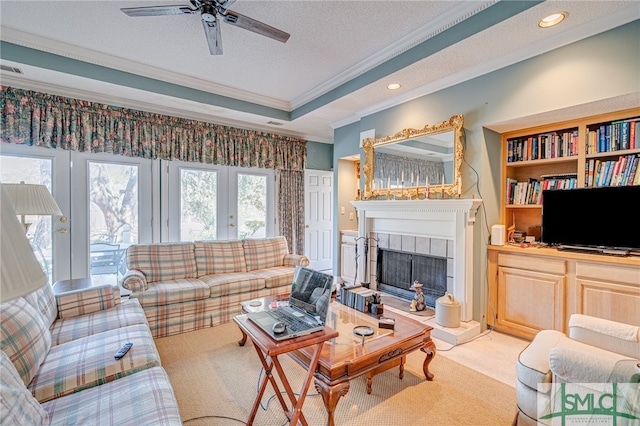 carpeted living room with crown molding, ceiling fan, a textured ceiling, a tiled fireplace, and french doors