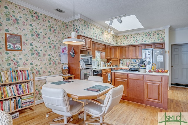 kitchen with pendant lighting, ornamental molding, stainless steel appliances, and a textured ceiling