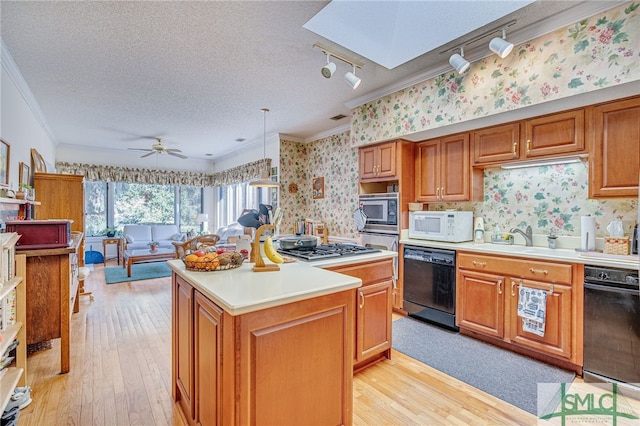 kitchen with sink, decorative light fixtures, a textured ceiling, a kitchen island, and stainless steel appliances