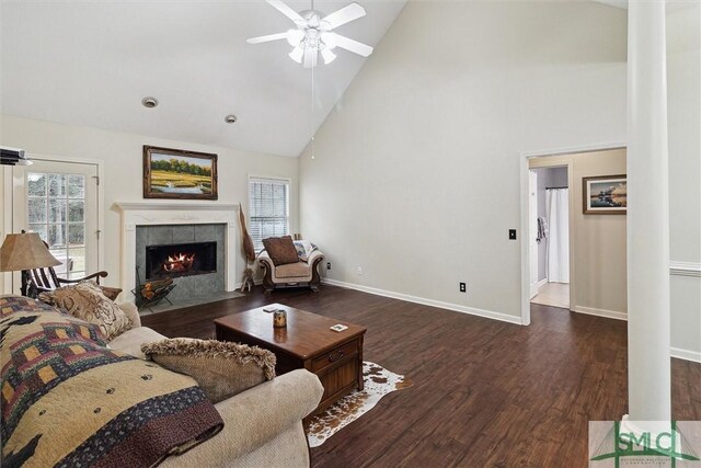 living room featuring high vaulted ceiling, a tile fireplace, dark hardwood / wood-style floors, and ceiling fan