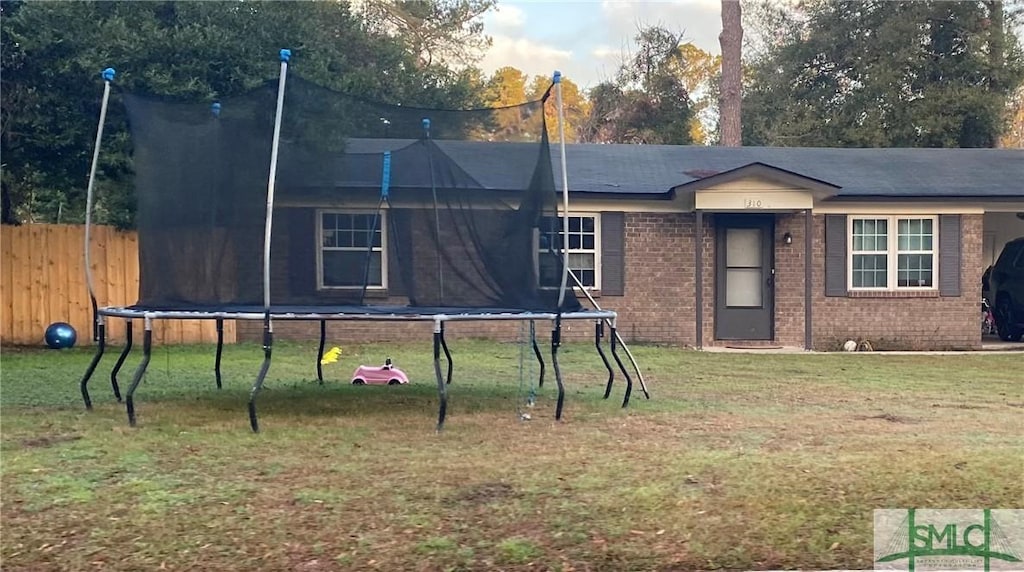 view of front of property with a trampoline and a front yard