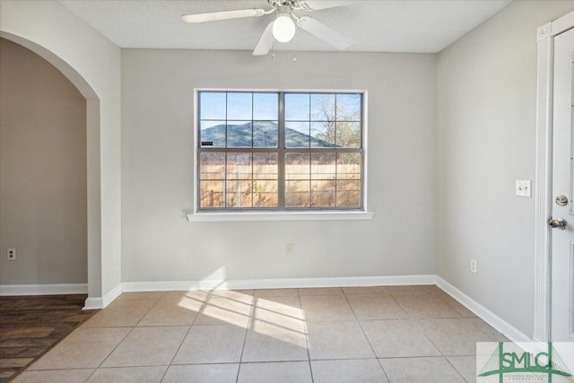 spare room with tile patterned flooring, a mountain view, and ceiling fan