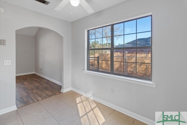 empty room featuring tile patterned floors, a healthy amount of sunlight, and a mountain view