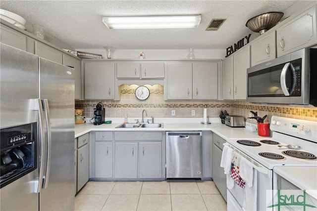 kitchen with light tile patterned flooring, sink, a textured ceiling, appliances with stainless steel finishes, and decorative backsplash