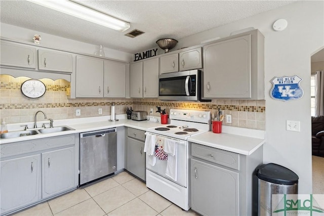 kitchen featuring light tile patterned flooring, sink, tasteful backsplash, appliances with stainless steel finishes, and gray cabinets