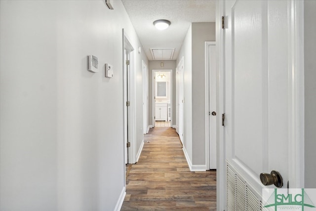 corridor with hardwood / wood-style floors and a textured ceiling