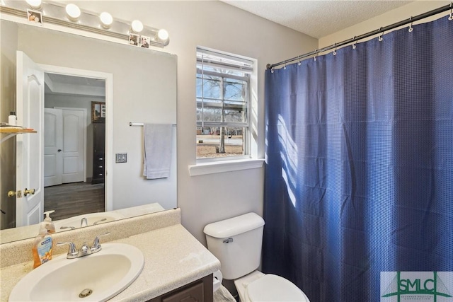 bathroom featuring vanity, a textured ceiling, toilet, and walk in shower