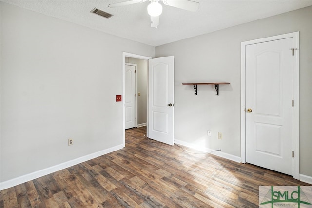 empty room featuring dark wood-type flooring, ceiling fan, and a textured ceiling