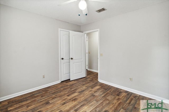 unfurnished bedroom featuring ceiling fan, dark hardwood / wood-style flooring, and a textured ceiling