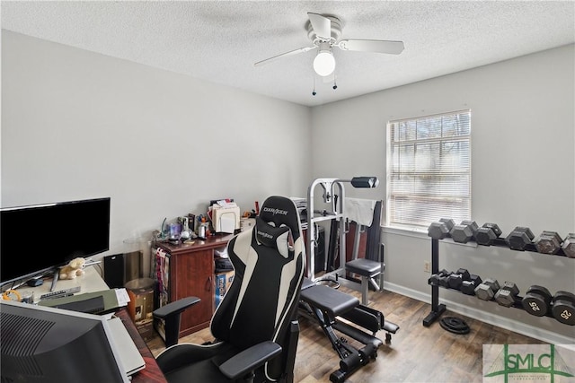 workout room with ceiling fan, hardwood / wood-style floors, and a textured ceiling