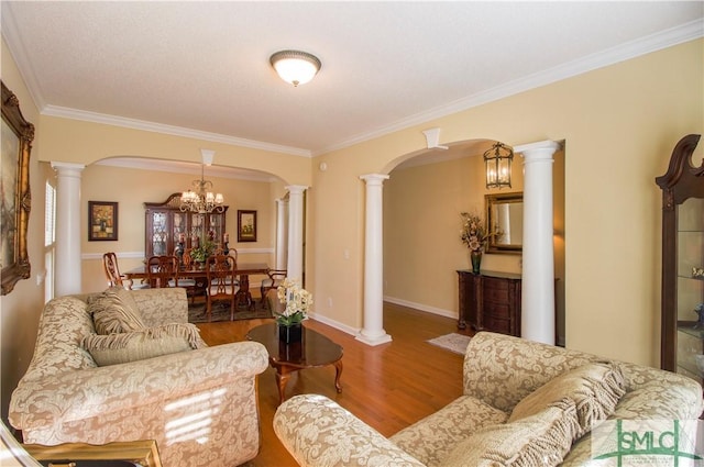 living room with crown molding, wood-type flooring, and decorative columns