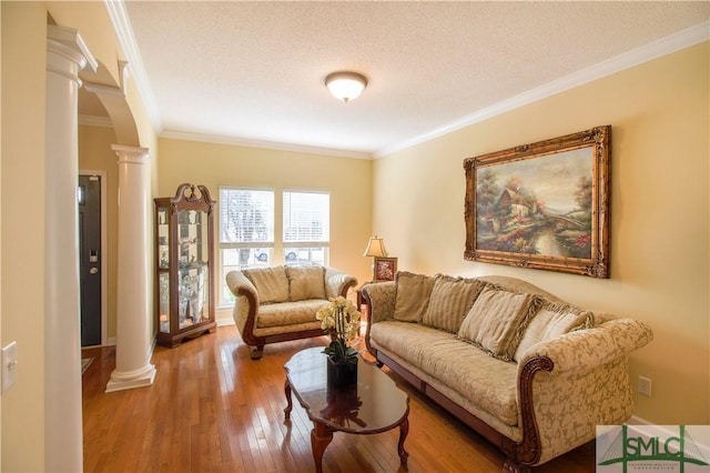 living room with hardwood / wood-style flooring, crown molding, decorative columns, and a textured ceiling