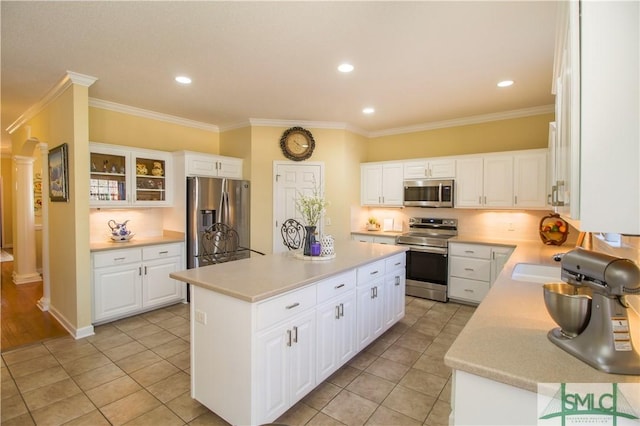 kitchen featuring white cabinetry, a kitchen island, ornate columns, and appliances with stainless steel finishes