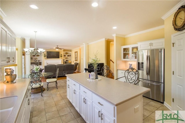 kitchen with stainless steel refrigerator with ice dispenser, ornamental molding, a kitchen island, and white cabinets