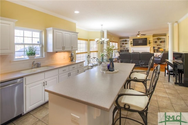 kitchen with a kitchen bar, sink, white cabinetry, decorative light fixtures, and stainless steel dishwasher