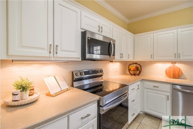 kitchen featuring stainless steel appliances, crown molding, light tile patterned floors, and white cabinets