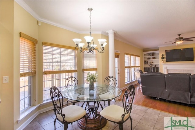 dining space with light tile patterned floors, crown molding, ceiling fan with notable chandelier, and built in shelves