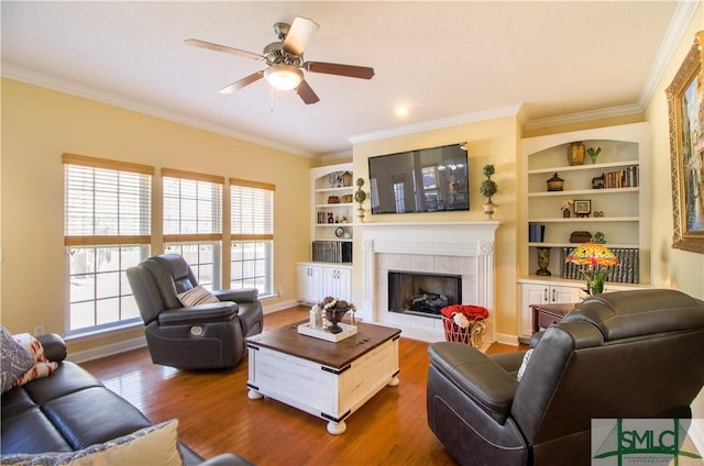 living room with a tiled fireplace, crown molding, and hardwood / wood-style floors