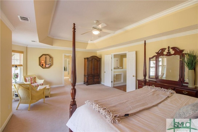 carpeted bedroom featuring ornamental molding, a tray ceiling, and ensuite bathroom