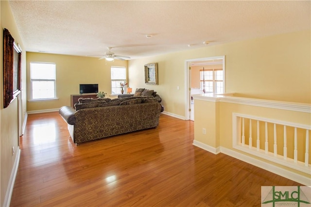 living room featuring ceiling fan, hardwood / wood-style flooring, a wealth of natural light, and a textured ceiling