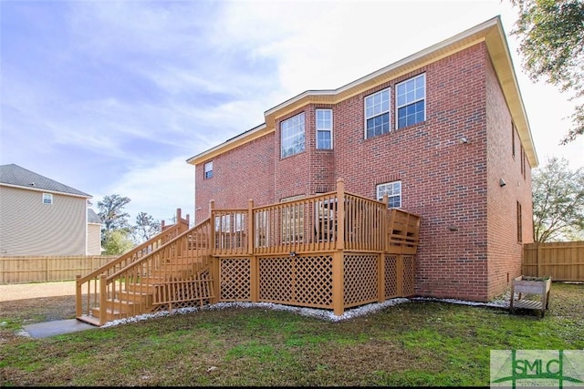 rear view of house featuring a wooden deck and a lawn