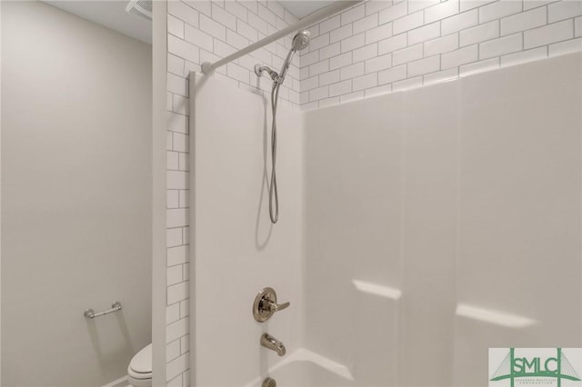 bathroom featuring tiled shower / bath combo and toilet