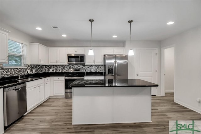 kitchen with sink, appliances with stainless steel finishes, a kitchen island, pendant lighting, and white cabinets