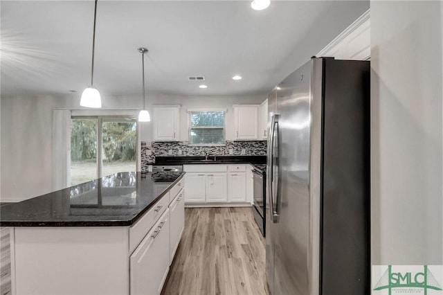 kitchen featuring black electric range oven, stainless steel refrigerator, white cabinets, and a kitchen island