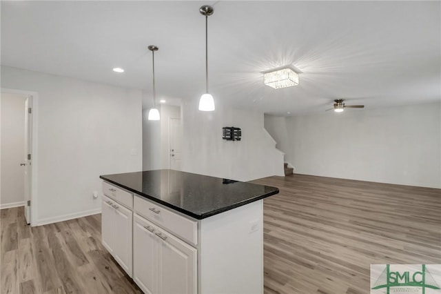 kitchen featuring hanging light fixtures, a center island, white cabinets, and light hardwood / wood-style flooring