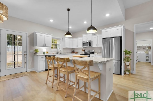 kitchen featuring sink, hanging light fixtures, appliances with stainless steel finishes, a kitchen island, and white cabinets