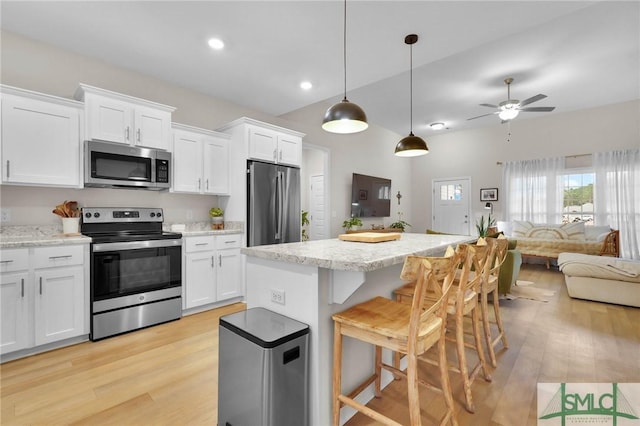 kitchen featuring light hardwood / wood-style flooring, appliances with stainless steel finishes, white cabinets, a kitchen island, and decorative light fixtures