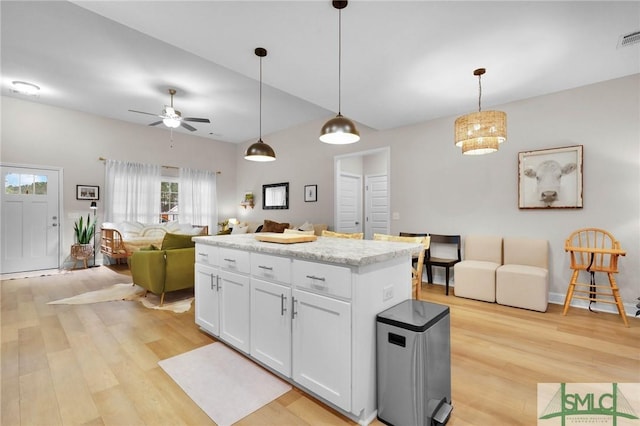 kitchen with white cabinetry, a center island, light hardwood / wood-style flooring, pendant lighting, and ceiling fan