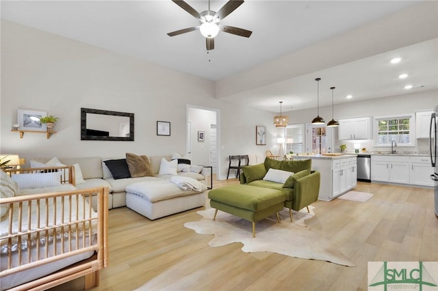 living room with sink, ceiling fan, and light hardwood / wood-style flooring