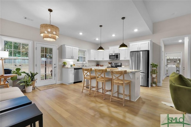 kitchen with pendant lighting, stainless steel appliances, a center island, and white cabinets