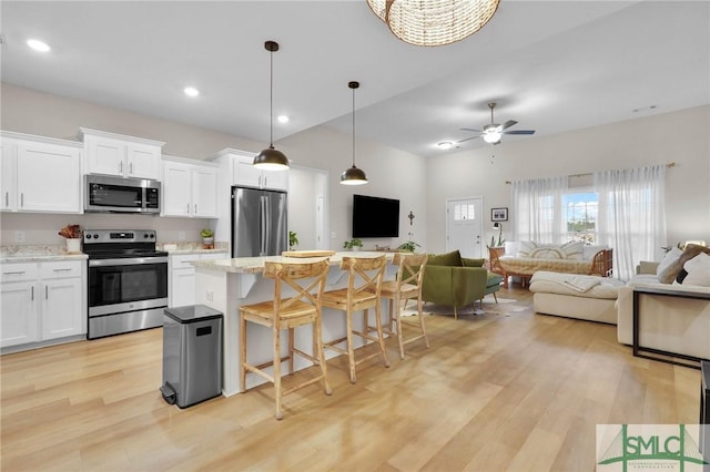 kitchen featuring a kitchen island, pendant lighting, white cabinetry, a kitchen breakfast bar, and stainless steel appliances