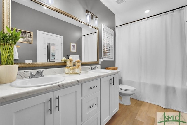 full bathroom with hardwood / wood-style flooring, vanity, toilet, and shower / bath combo