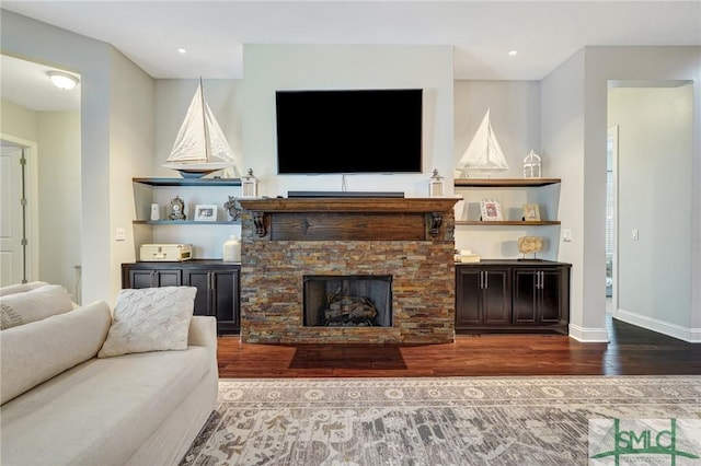 living room featuring wood-type flooring and a stone fireplace