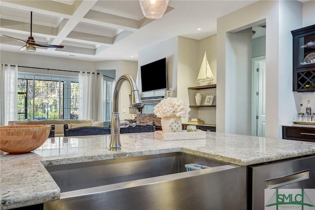 kitchen featuring sink, ceiling fan, coffered ceiling, light stone counters, and beamed ceiling